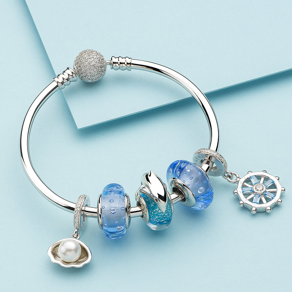 Charm bracelet styled with dolphin Murano glass bead and matching marine-themed charms