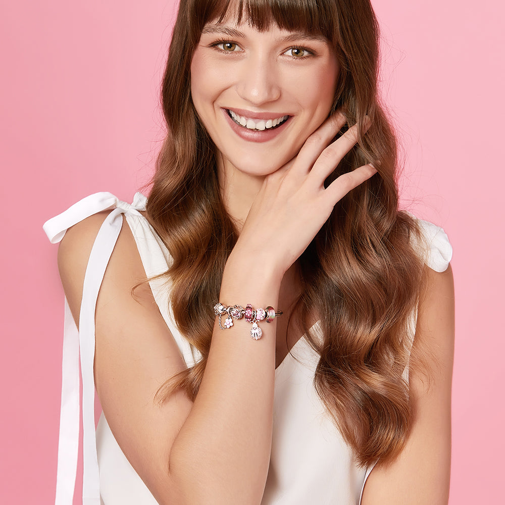 ATHENAIE butterfly and daisy charm styled with other pink beads on model wrist