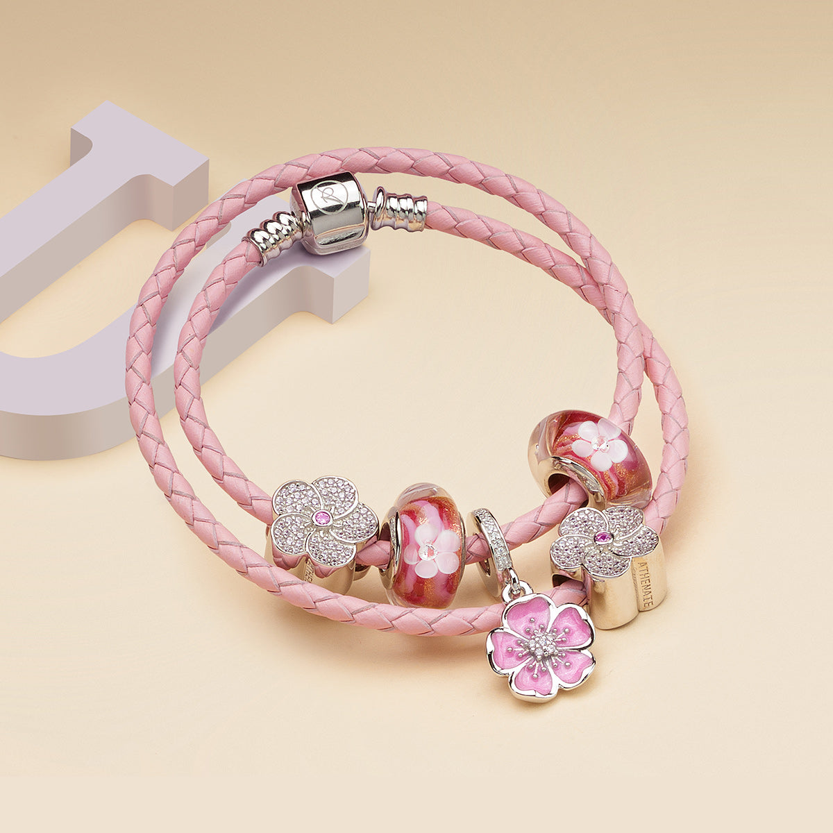 Blush Plum Blossom charm pendant styled on silver charm bracelet, elegant floral design for gifting and everyday wear