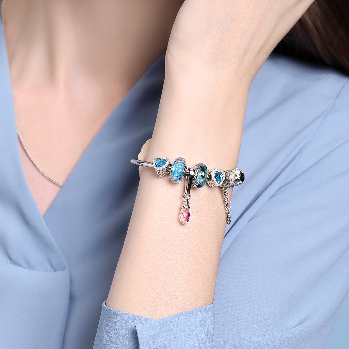 Woman wearing Dolphin Dance Murano glass charm with bracelet, elegant ocean bead styling