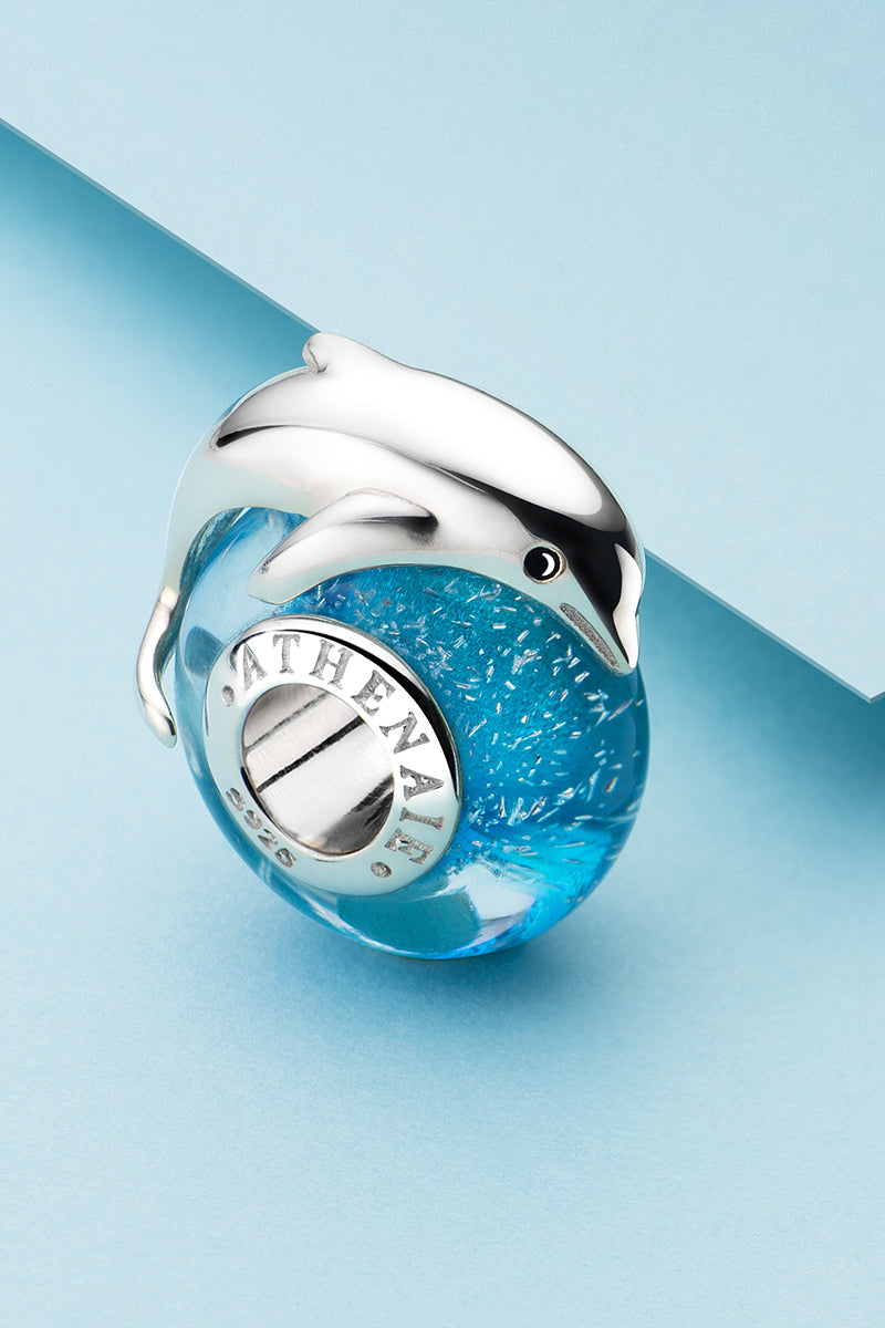 Close-up detail of dolphin Murano glass charm bead crafted with sterling silver core and ocean blue glass design