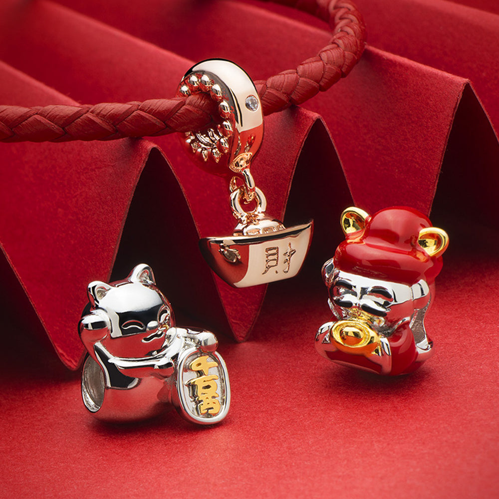 Fortune Kitty charm bead with 18K gold and CZ displayed in a Chinese New Year themed jewelry scene