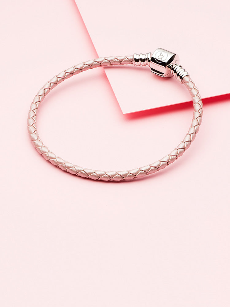 Braided leather charm bracelet styled on wrist with charms