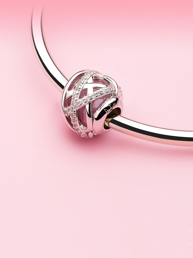 Pink Embrace sterling silver charm bead with soft pink design displayed on charm bracelet