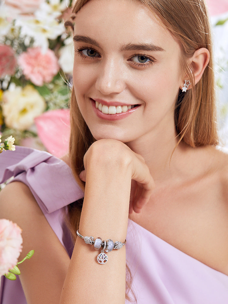 Woman wearing a charm bracelet with the rose pink wave Murano glass bead