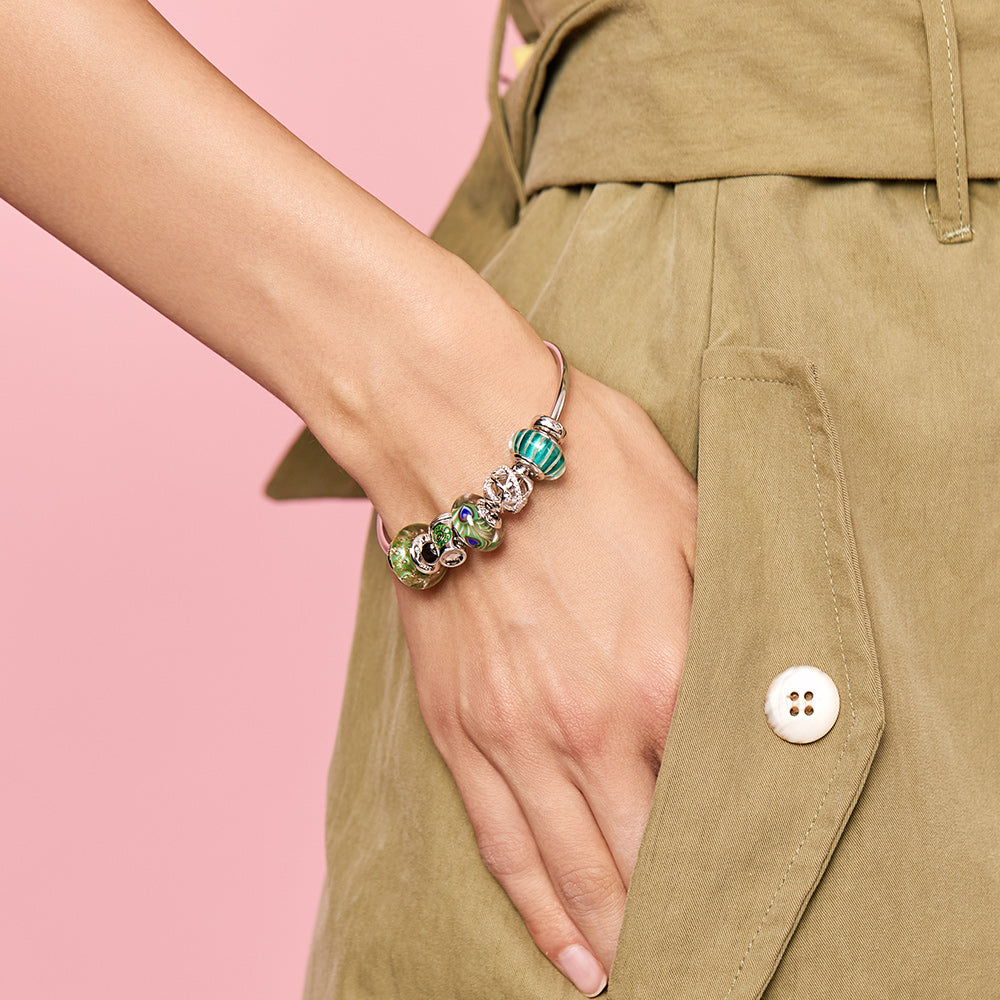 Close-up of Royal Feather Murano glass charm bead on model’s wrist.