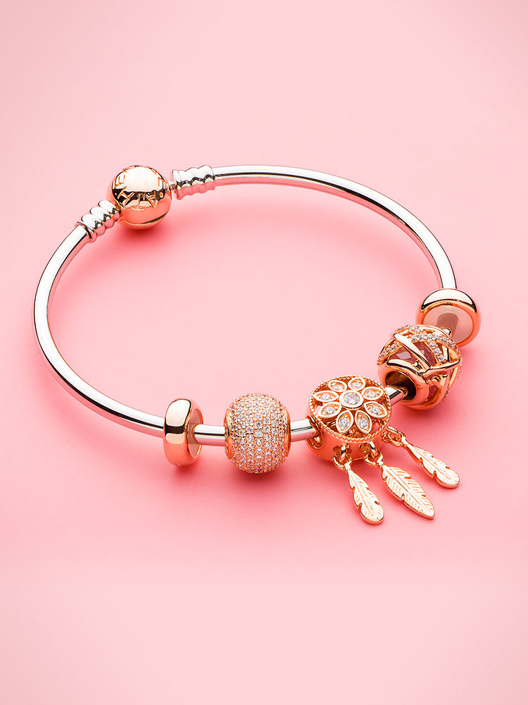 sterling silver charm bangle bracelet with rose gold clasp styled with charms