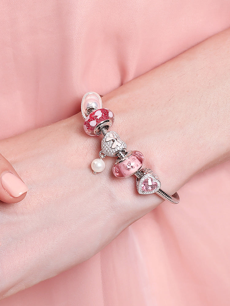 Sterling silver charm bracelet worn on wrist with heart clasp detail